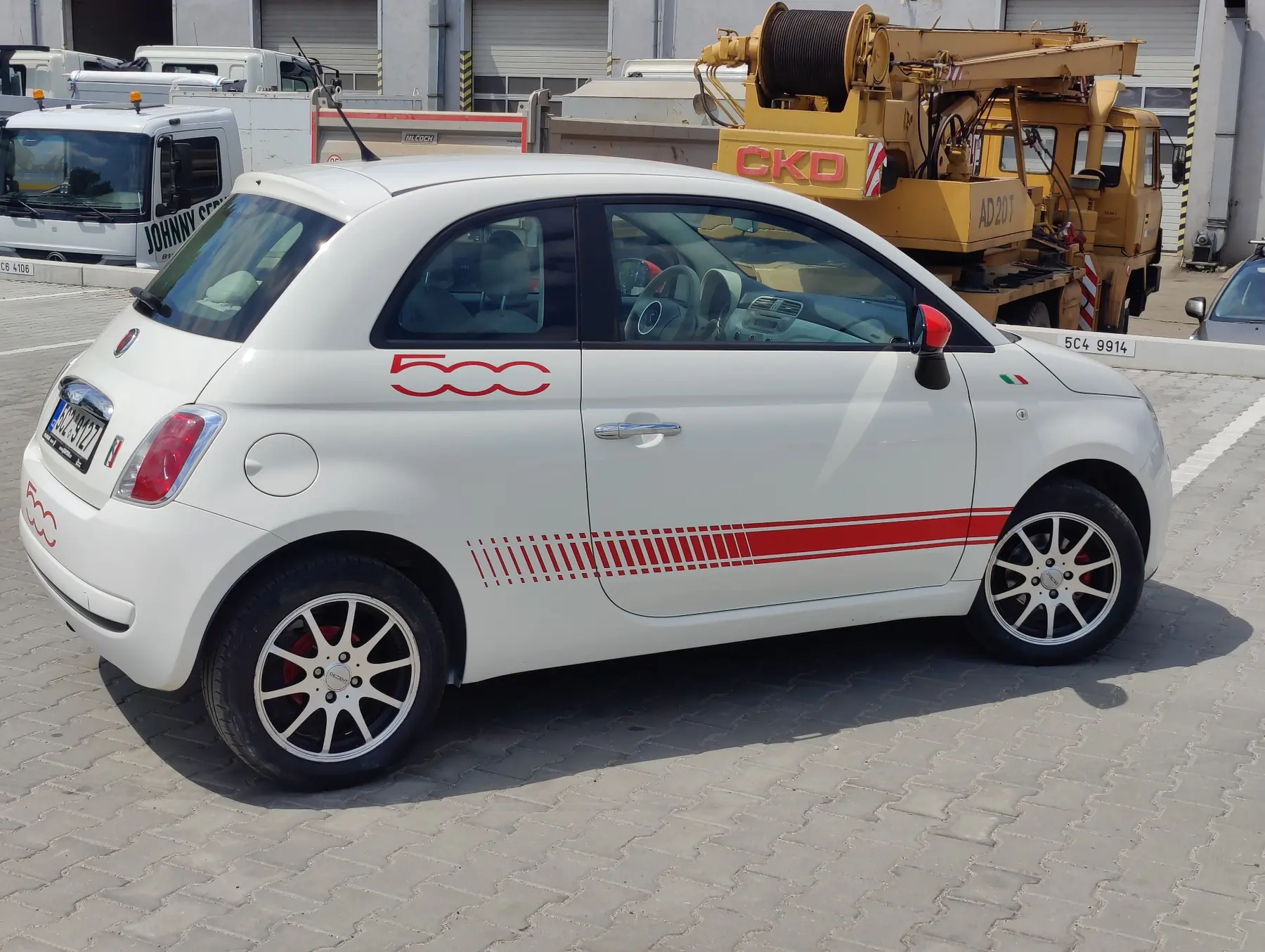 Červené sportovní pruhy a označení na bílém vozu Fiat 500